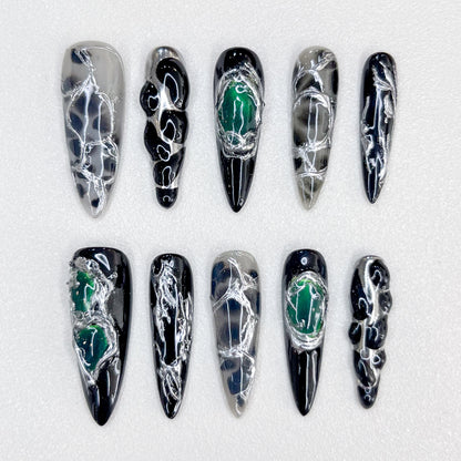 Midnight Web press-on nails with intricate black and silver patterns, accented with green details for a bold, enigmatic look.