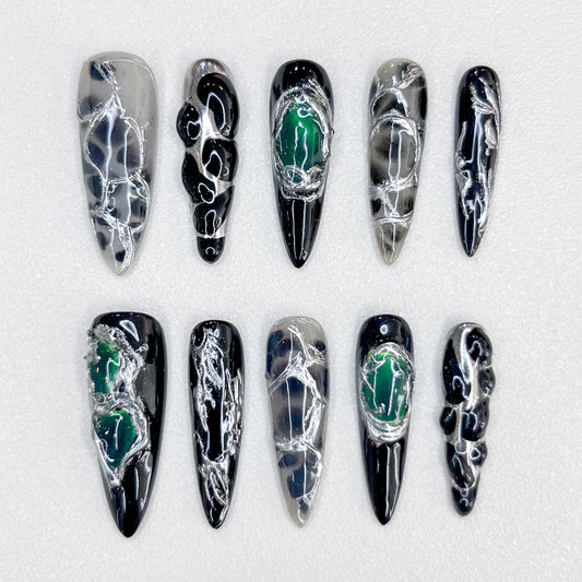 Midnight Web press-on nails with intricate black and silver patterns, accented with green details for a bold, enigmatic look.