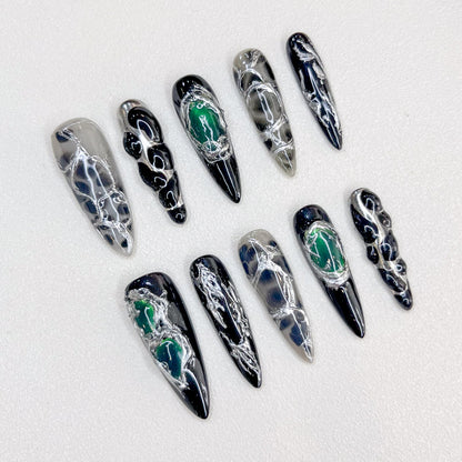 Midnight Web press-on nails with intricate black and silver patterns, accented with green details for a bold, enigmatic look.