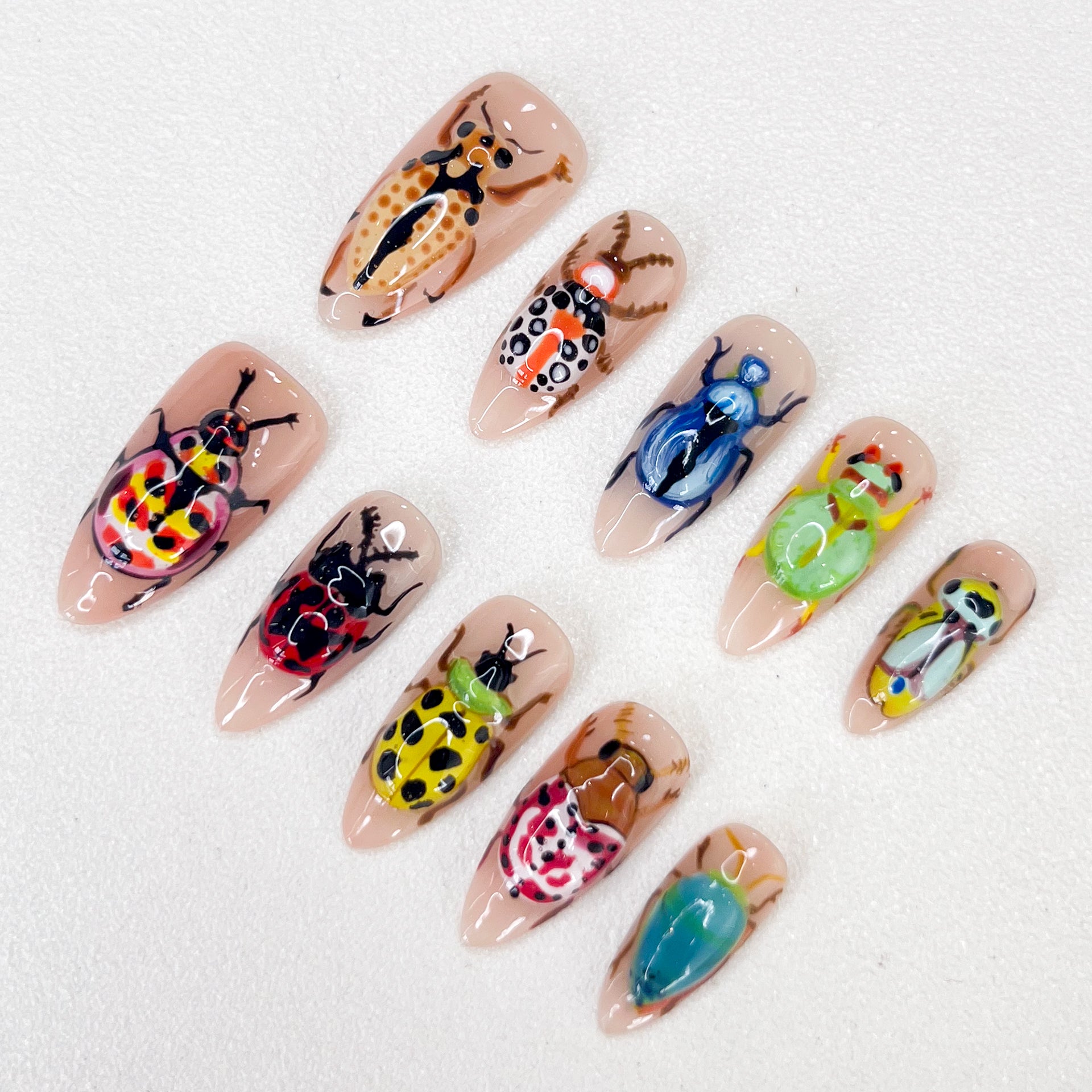 Beetle Garden press-on nails with intricate beetle artwork and vibrant natural hues for a daring look.