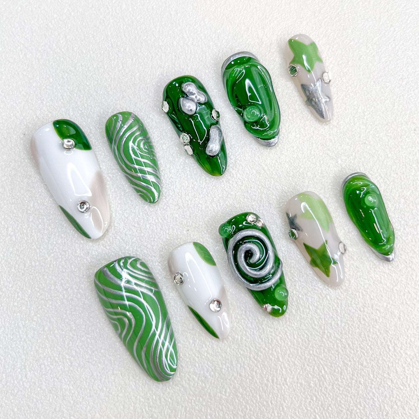 Verdant Whispers press-on nails with clean lines and green hues, accented with intricate spiral and metallic details.