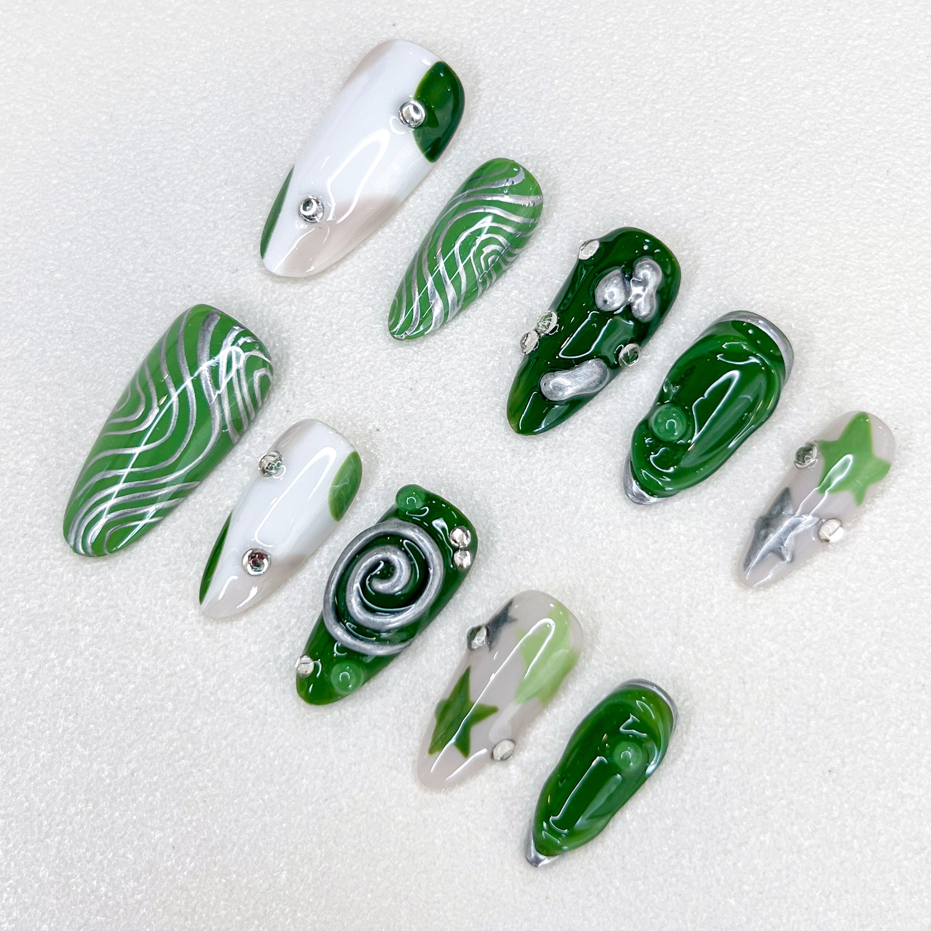 Verdant Whispers press-on nails with clean lines and green hues, accented with intricate spiral and metallic details.