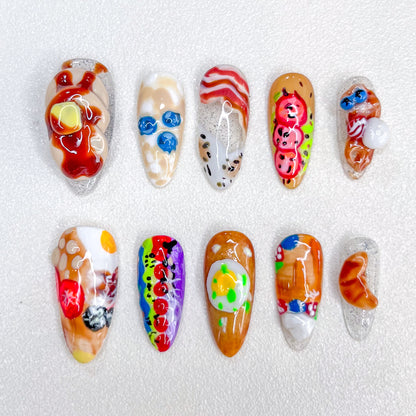 Gourmet Dreams press-on nails with breakfast-inspired designs, including 3D food art like bacon and eggs.