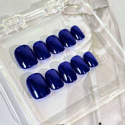 A set of deep blue glossy press - on nails neatly arranged in a transparent case, featuring a luxurious and smooth finish, ideal for formal or evening wear, with a deep and captivating color.