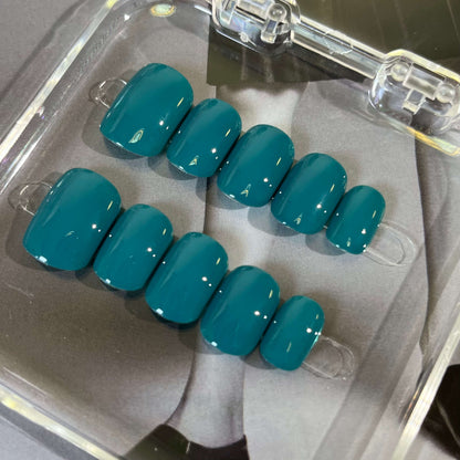 A set of teal glossy press - on nails neatly placed in a transparent box, showcasing a cool, smooth finish, ideal for beach or summer events.