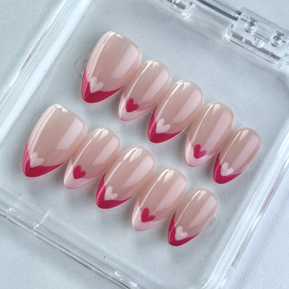 Nude nails with bold red French tips, each adorned with alternating red and white heart accents. This heartfelt design exudes romance and timeless elegance, perfect for adding a touch of love to your style.