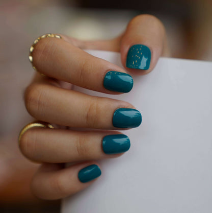 A set of teal glossy press - on nails neatly placed in a transparent box, showcasing a cool, smooth finish, ideal for beach or summer events.