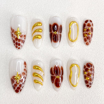 This is a press-on nail set featuring brown and gold tones with intricate marble patterns, floral motifs, and glossy textures. Designed for a stylish and luxurious appearance.