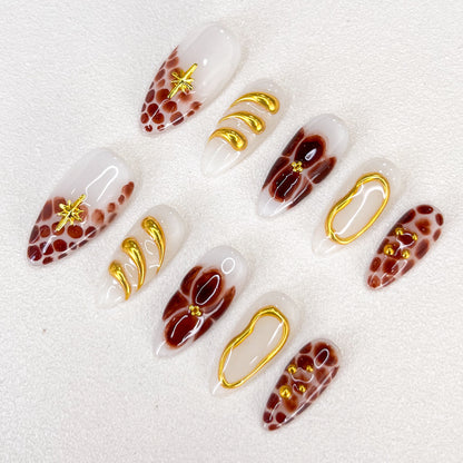 This is a press-on nail set featuring brown and gold tones with intricate marble patterns, floral motifs, and glossy textures. Designed for a stylish and luxurious appearance.