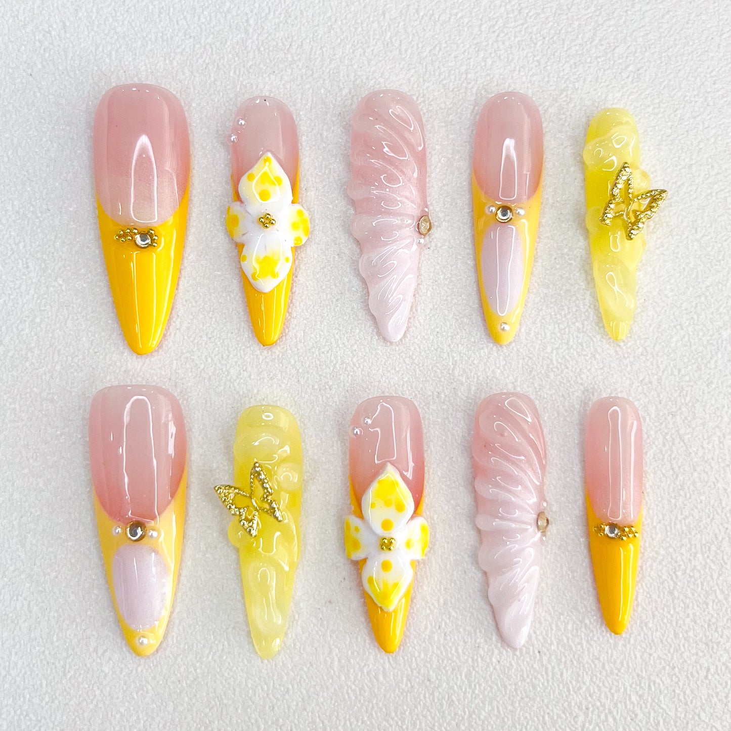 Sunshine Elegance press-on nails with yellow and pink hues, decorated with intricate butterfly and floral designs, adding a bright and feminine charm to any outfit.