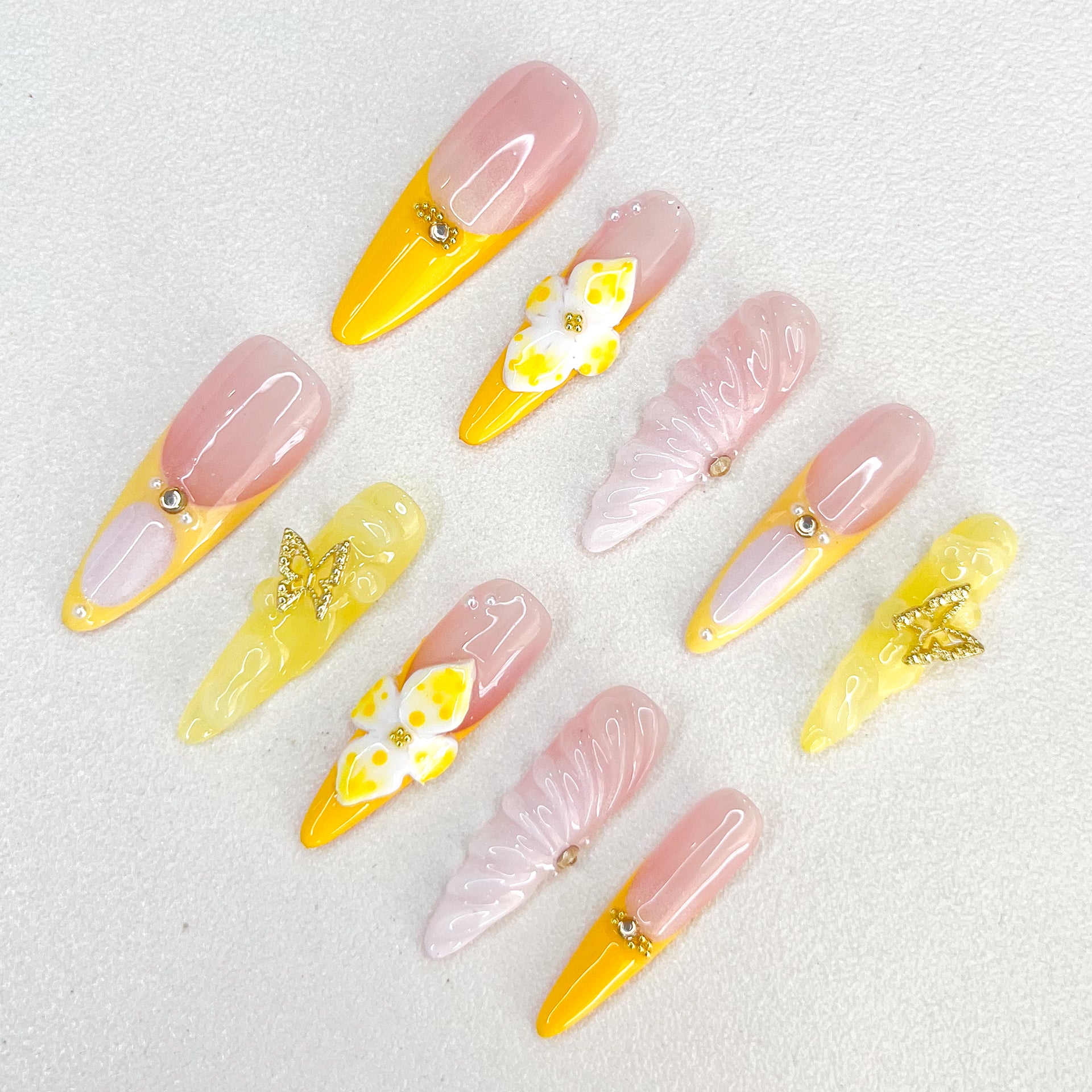 Sunshine Elegance press-on nails with yellow and pink hues, decorated with intricate butterfly and floral designs, adding a bright and feminine charm to any outfit.