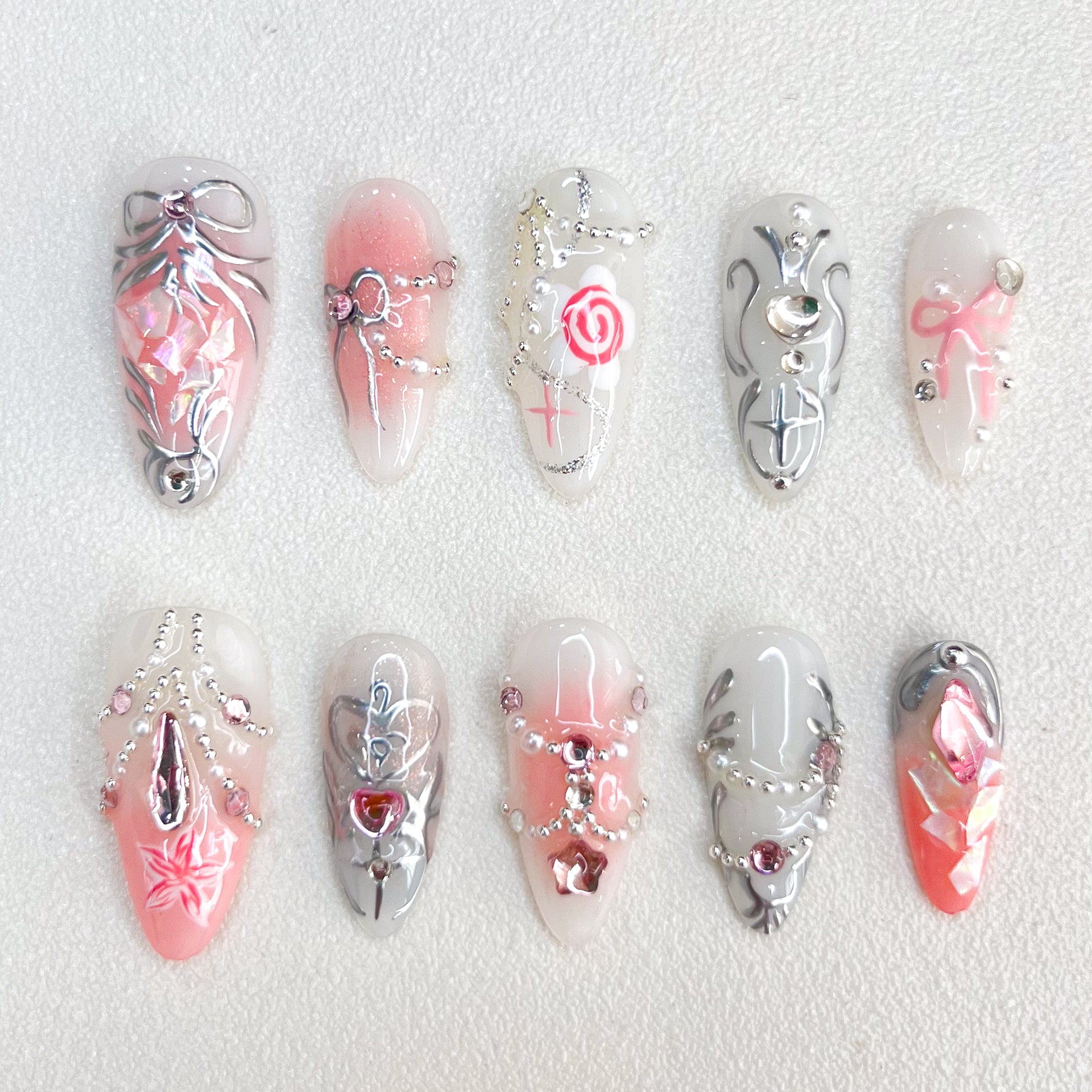 Rose Reverie press-on nails with pink and silver hues, adorned with roses and chain accents, creating a whimsical and luxurious style.