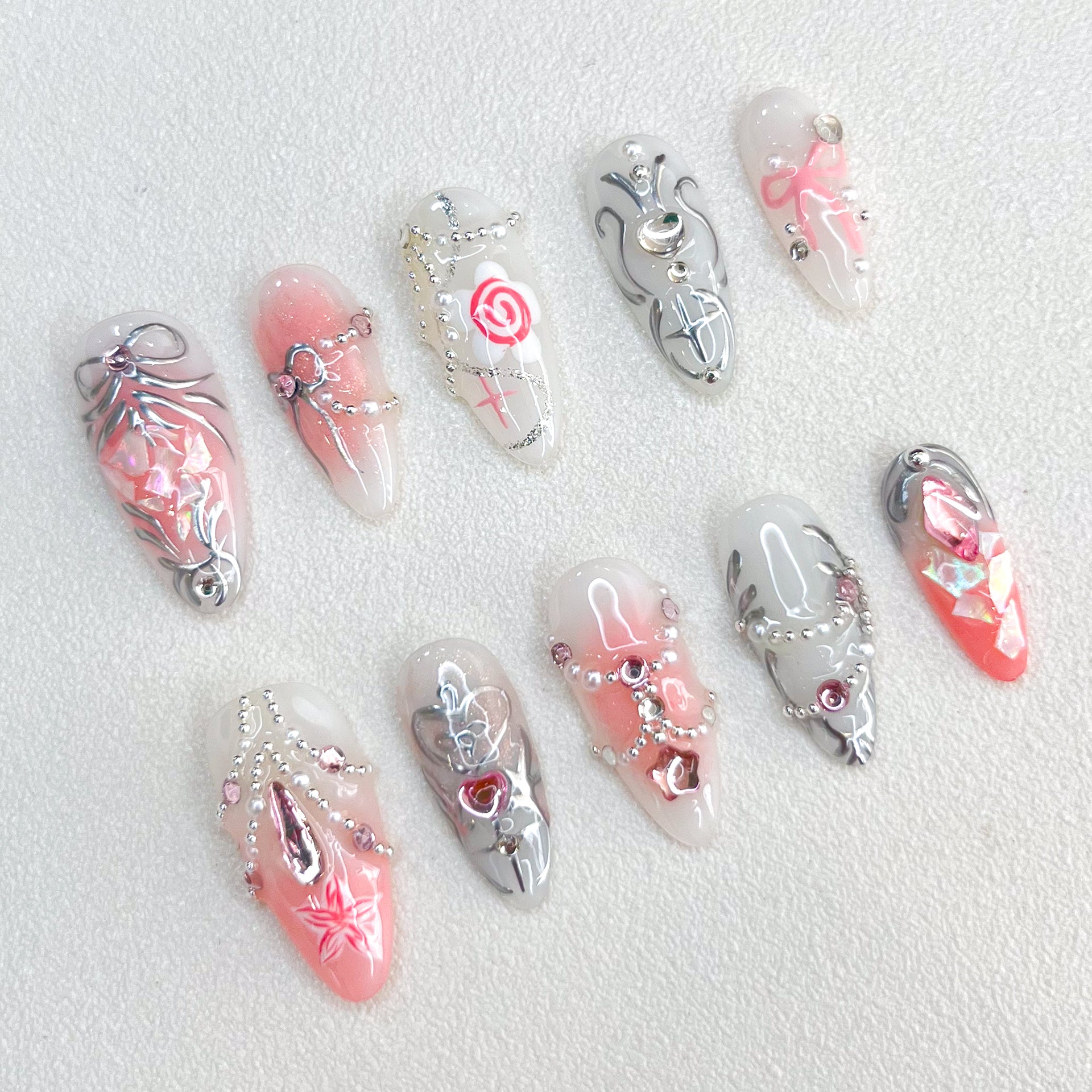 Rose Reverie press-on nails with pink and silver hues, adorned with roses and chain accents, creating a whimsical and luxurious style.