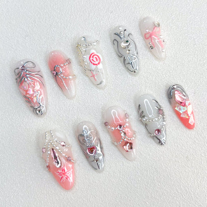 Rose Reverie press-on nails with pink and silver hues, adorned with roses and chain accents, creating a whimsical and luxurious style.