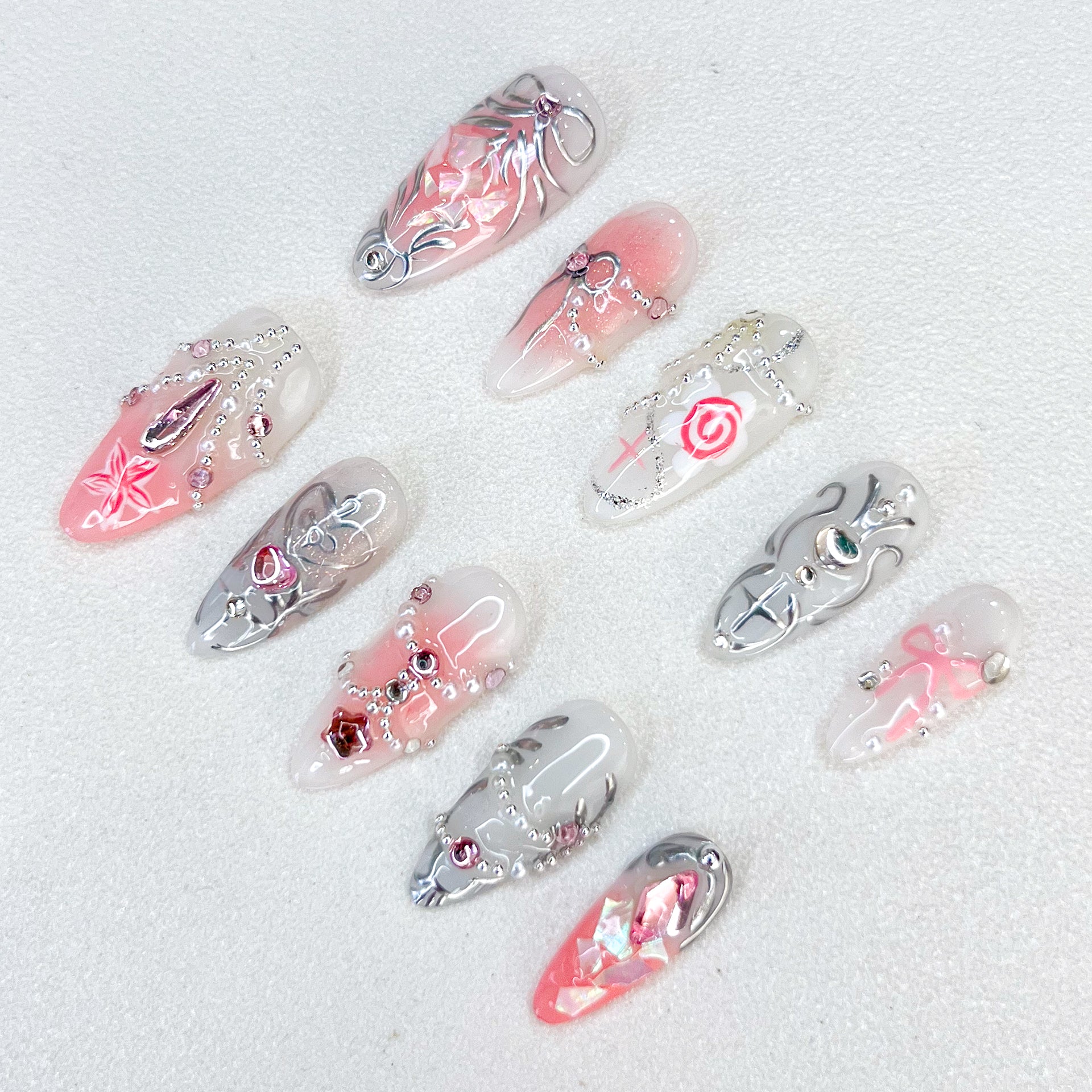 Rose Reverie press-on nails with pink and silver hues, adorned with roses and chain accents, creating a whimsical and luxurious style.