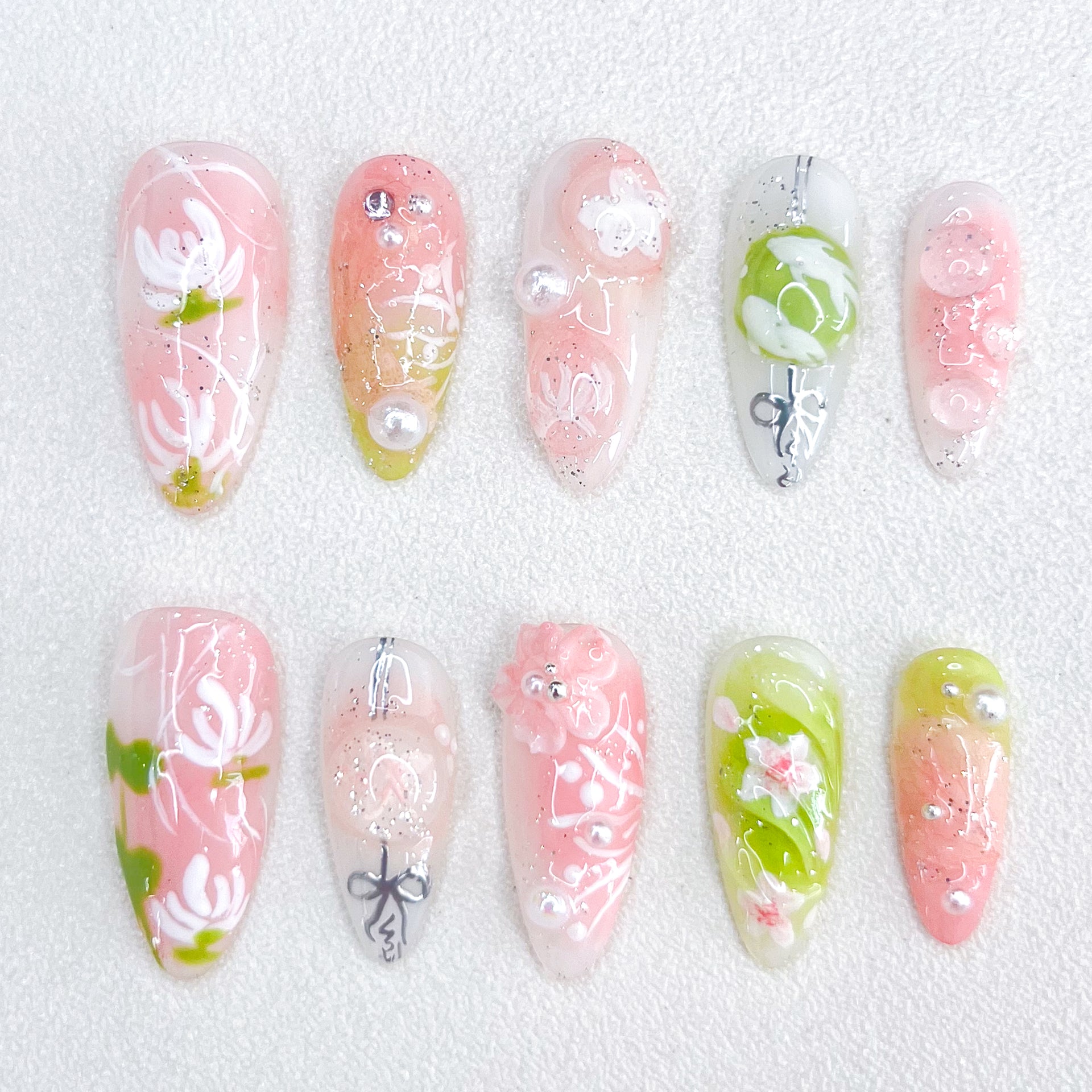 A set of press - on nails with soft pastel colors and delicate floral designs, including leaves and pearl accents. The nails have an ethereal and tranquil appearance, suitable for spring outings or afternoon tea parties.