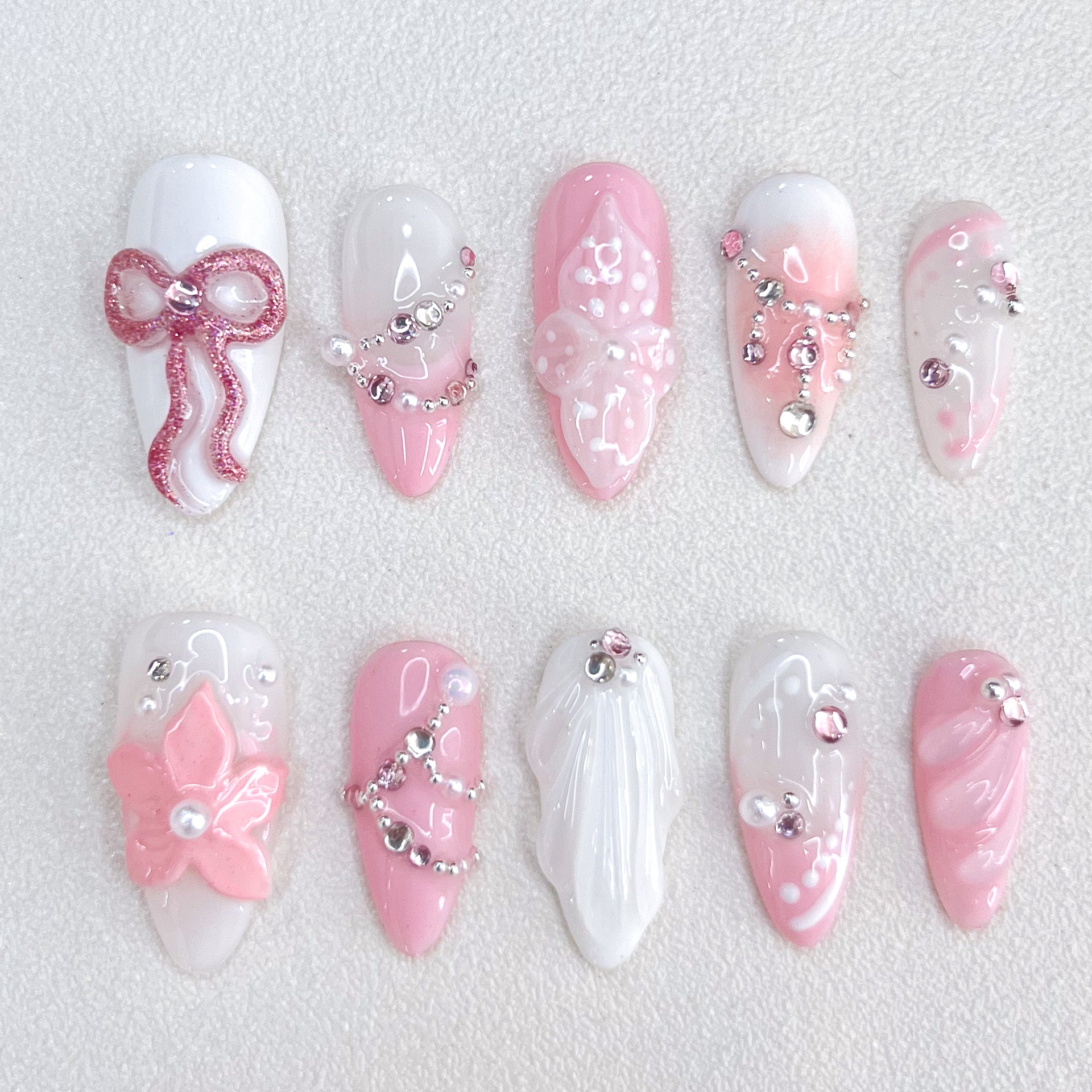 Blushing Elegance press-on nails with pink and white gradient design, adorned with bows, florals, and shimmering gems for a romantic and sophisticated look.