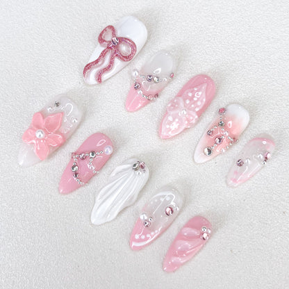 Blushing Elegance press-on nails with pink and white gradient design, adorned with bows, florals, and shimmering gems for a romantic and sophisticated look.