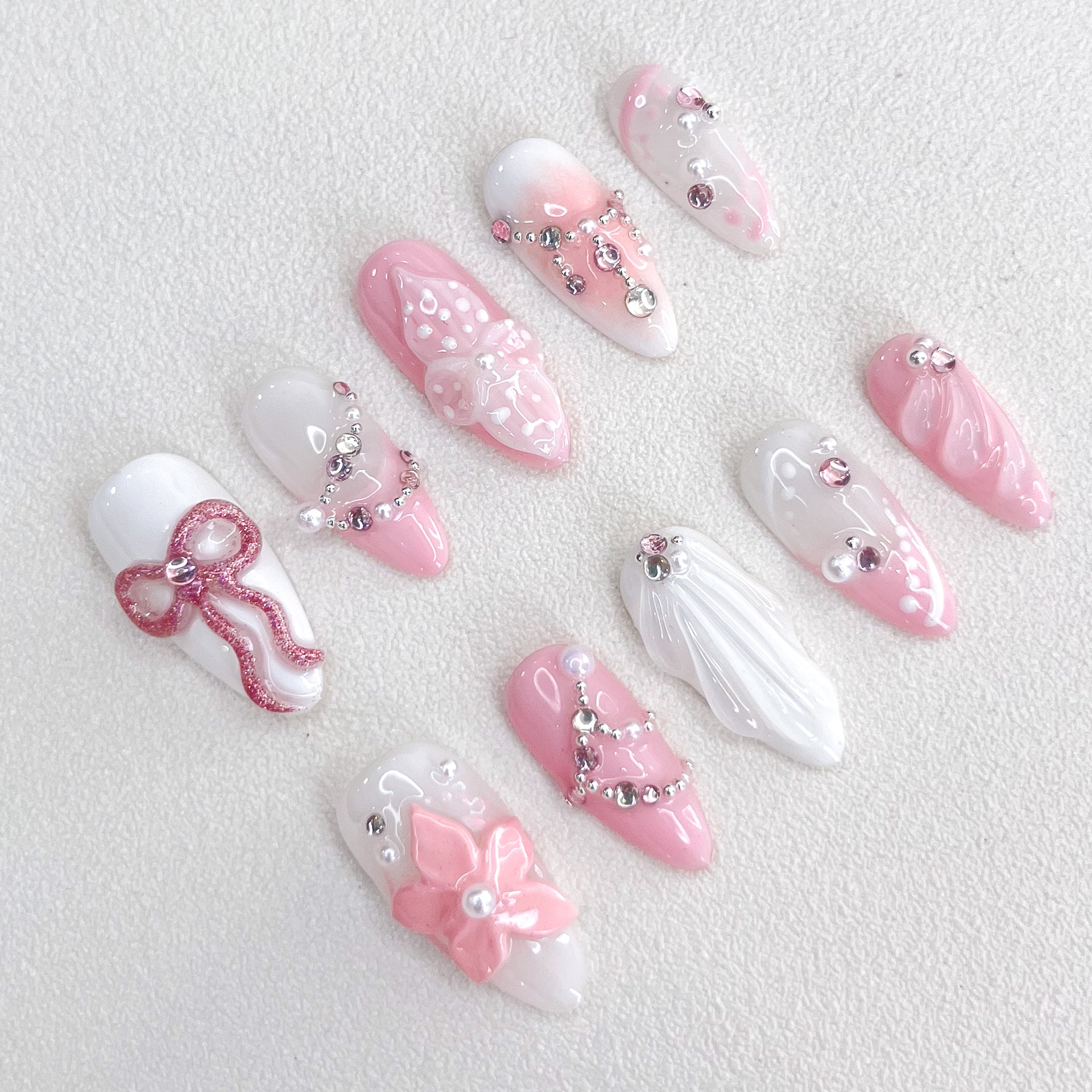 Blushing Elegance press-on nails with pink and white gradient design, adorned with bows, florals, and shimmering gems for a romantic and sophisticated look.