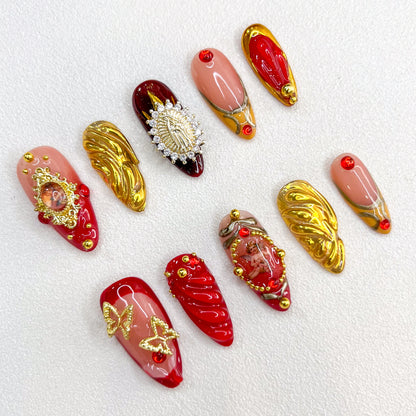 Golden Reverence press-on nails with intricate gold accents and angelic motifs, paired with rich red details for a vintage-inspired, timeless look.