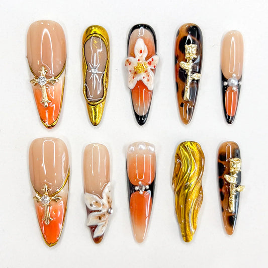 Amber Symphony press-on nails showcasing warm amber shades, ornate metallic designs, and classic accents for a luxurious statement.