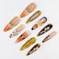 Amber Symphony press-on nails showcasing warm amber shades, ornate metallic designs, and classic accents for a luxurious statement.