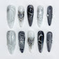 Cosmic Noir press-on nails with bold black-and-silver gradients, starry details, and shimmering accents for a dazzling night-out style.
