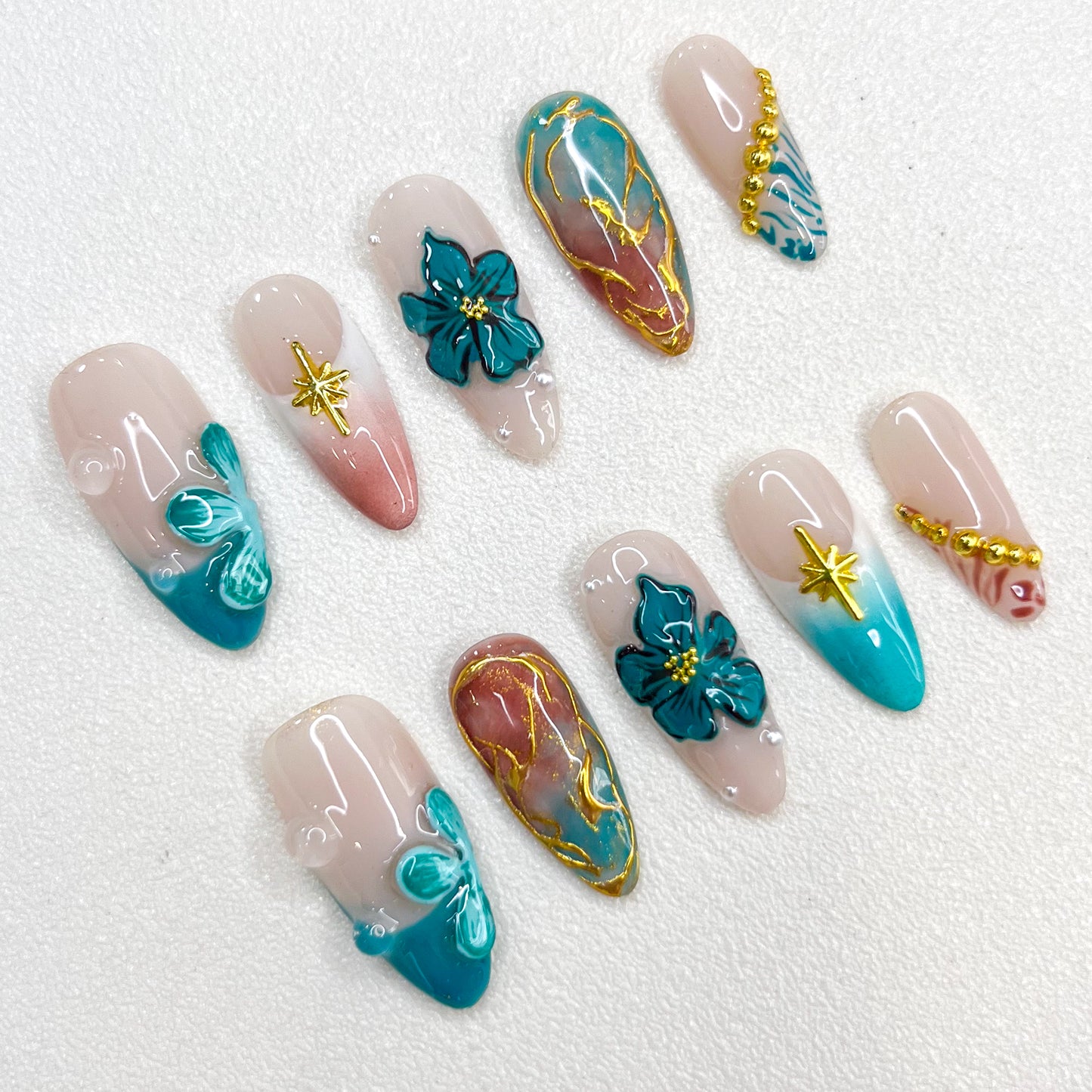 Tidal Serenity press-on nails with coastal-inspired tones, floral patterns, and golden details for a fresh and breezy aesthetic.