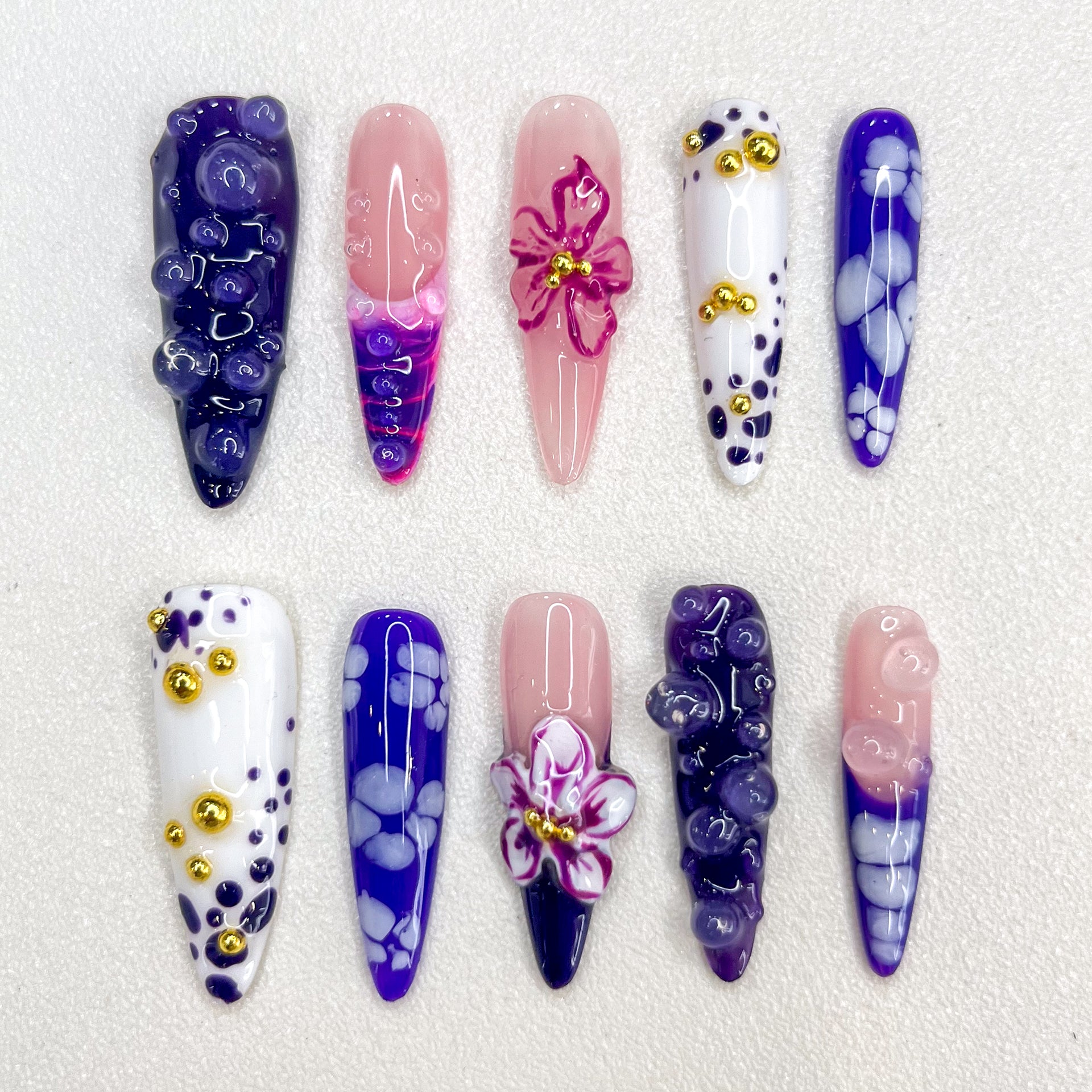 Amethyst Petals press-on nails with purple gradients, intricate floral designs, and golden accents that create a charming, luxurious look.