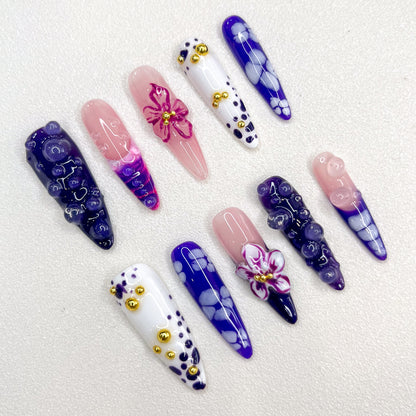 Amethyst Petals press-on nails with purple gradients, intricate floral designs, and golden accents that create a charming, luxurious look.