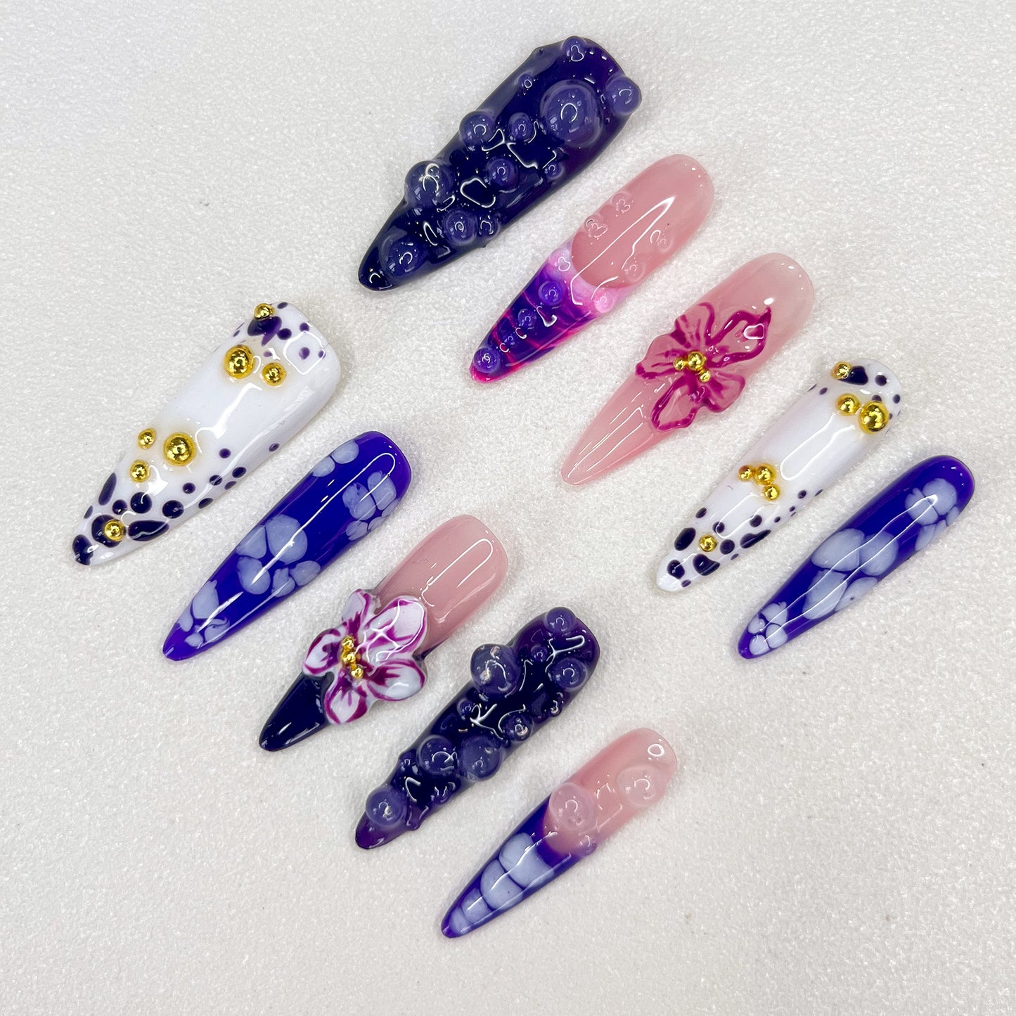 Amethyst Petals press-on nails with purple gradients, intricate floral designs, and golden accents that create a charming, luxurious look.