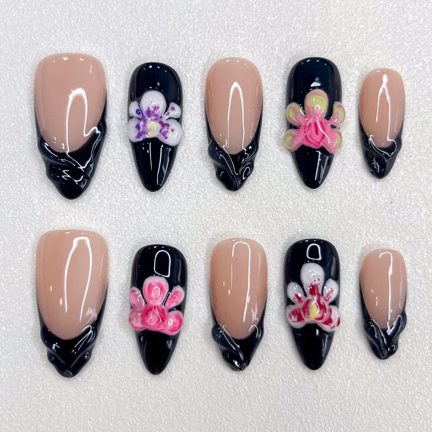 Midnight Orchid press-on nails with contrasting nude and black bases, highlighted by vibrant orchid details and glossy finishes for a modern, chic look.