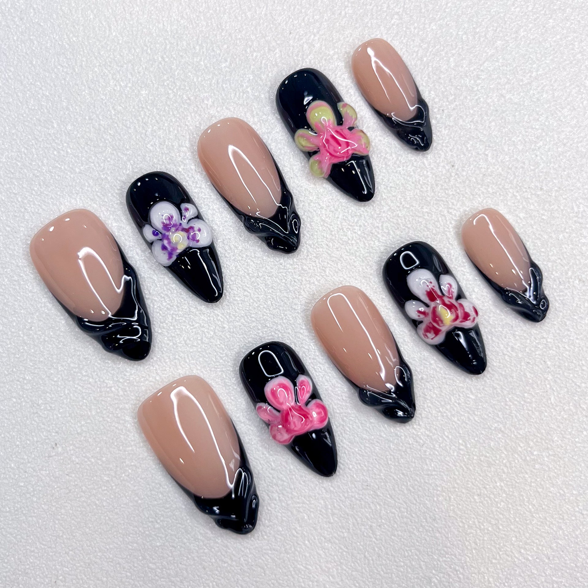 Midnight Orchid press-on nails with contrasting nude and black bases, highlighted by vibrant orchid details and glossy finishes for a modern, chic look.