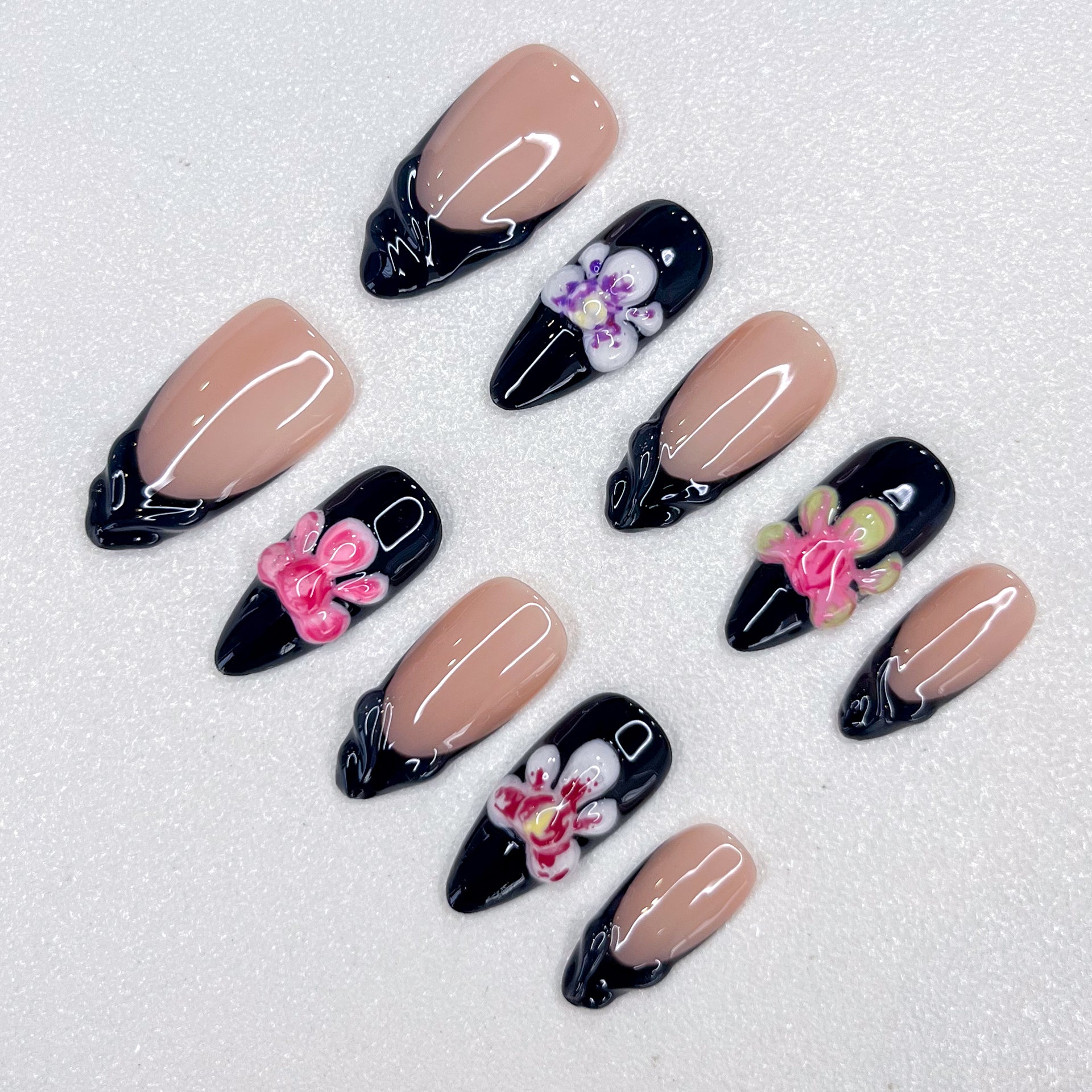 Midnight Orchid press-on nails with contrasting nude and black bases, highlighted by vibrant orchid details and glossy finishes for a modern, chic look.