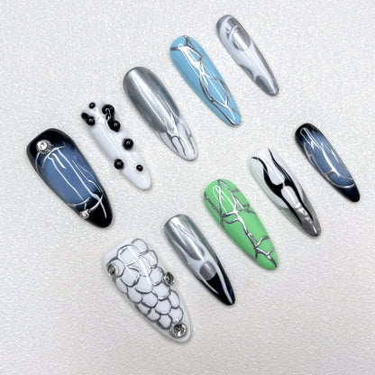 Press-on nails inspired by cyberpunk aesthetics, showcasing metallic silver veins across glossy black, green, blue, and white bases, accented with chrome details and geometric patterns for a bold techwear vibe.