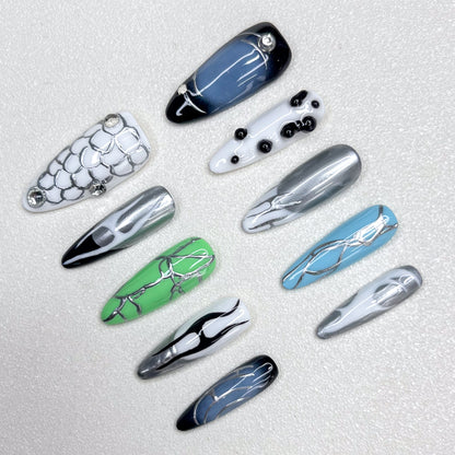 Press-on nails inspired by cyberpunk aesthetics, showcasing metallic silver veins across glossy black, green, blue, and white bases, accented with chrome details and geometric patterns for a bold techwear vibe.