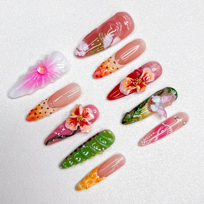 Colorful press-on nail set with tropical themes, showcasing 3D hibiscus flowers, butterflies, and floral gradients in pink, green, orange, and red, capturing a lush garden vibe.