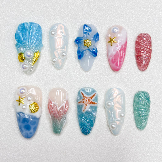 Mermaid-inspired press-on nails with blue and pink gradients, seashell textures, 3D pearls, gold seashell charms, and oceanic elements for dreamy undersea aesthetics.
