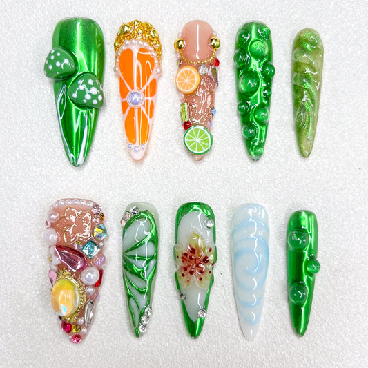 A vibrant nature-inspired press-on nail set with glossy green finishes, mushrooms, citrus fruits, flower petals, and gemstone embellishments, resembling a fantasy garden or enchanted forest.