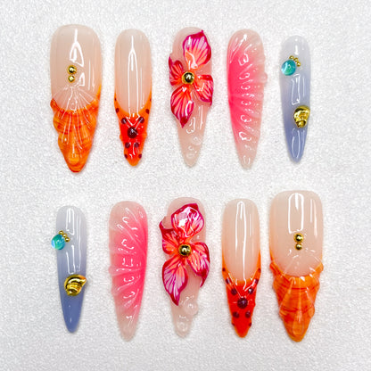 Press-on nails with fiery orange and pink flame tips, vivid hibiscus flower accents, soft gradient backgrounds, and gold studs. Featuring 3D floral textures and translucent jelly finishes, evoking tropical sunsets and vibrant blooms.