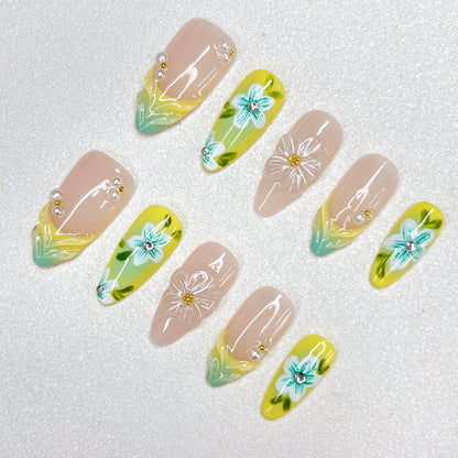 Press-on nails with a lemon-yellow and mint-green gradient design, decorated with 3D translucent flowers, hand-painted teal-blue blossoms, pearl accents, and nude-toned bases. A bright botanical-inspired summer nail set.