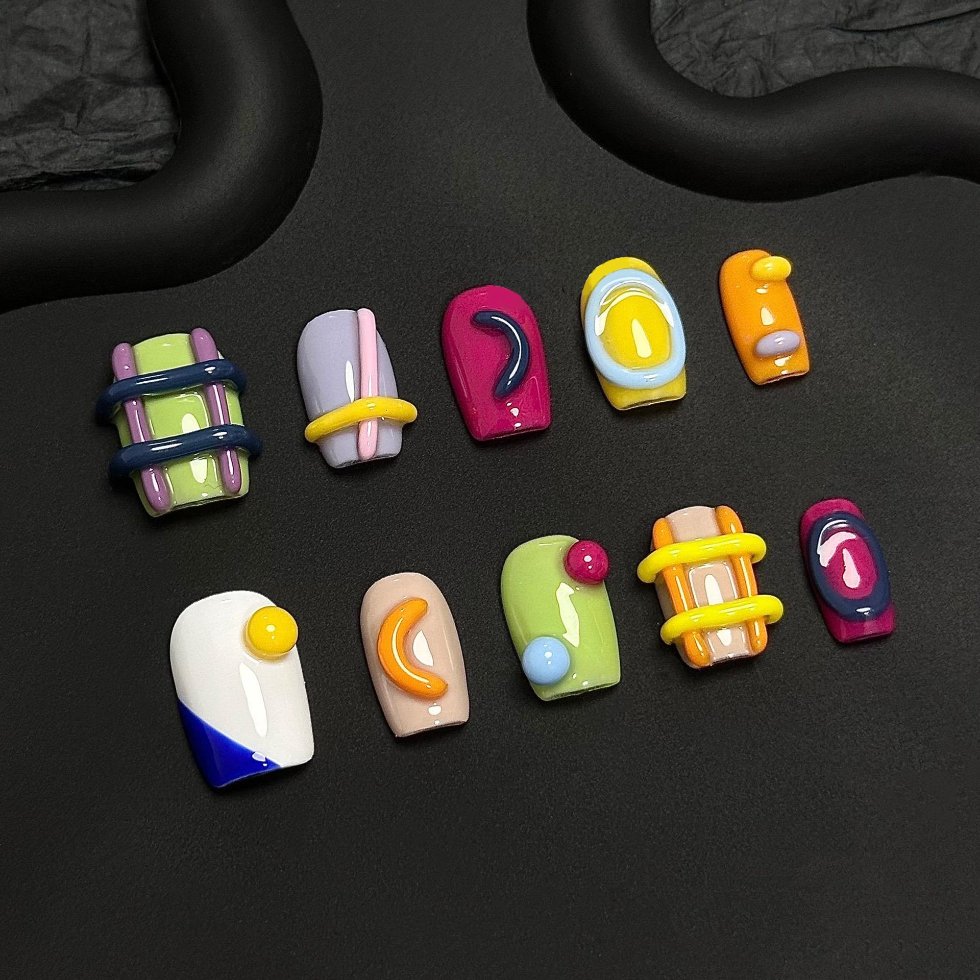 A press-on nail set featuring vibrant colors, raised 3D elements, and geometric patterns, creating a playful and modern artistic aesthetic.