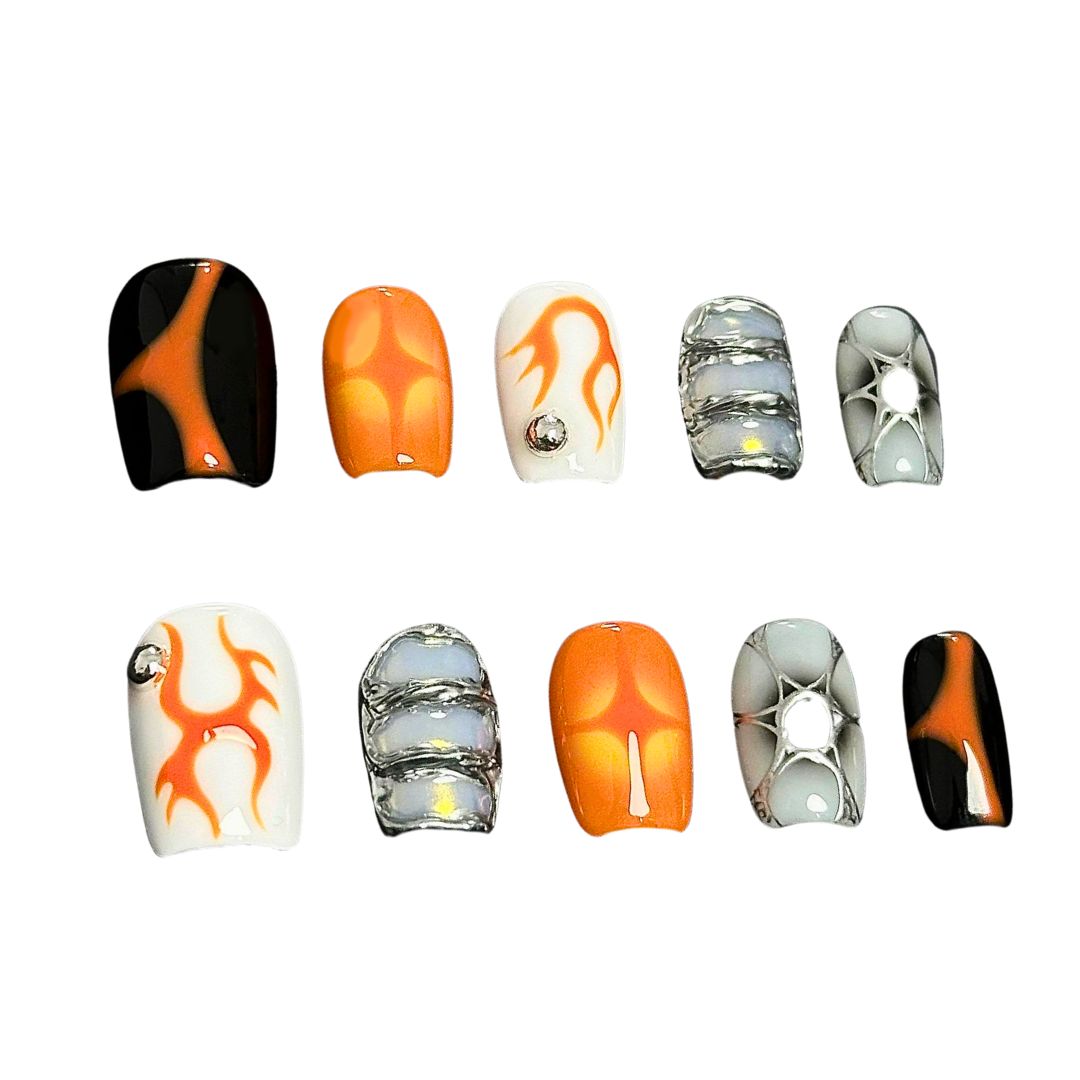 A press-on nail set with orange flame designs, glossy black and white bases, and metallic silver accents, creating a bold and futuristic aesthetic.