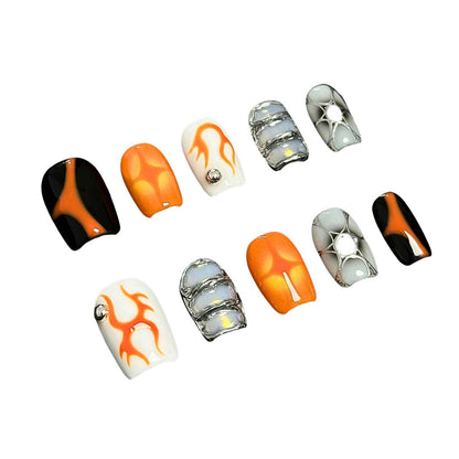 A press-on nail set with orange flame designs, glossy black and white bases, and metallic silver accents, creating a bold and futuristic aesthetic.