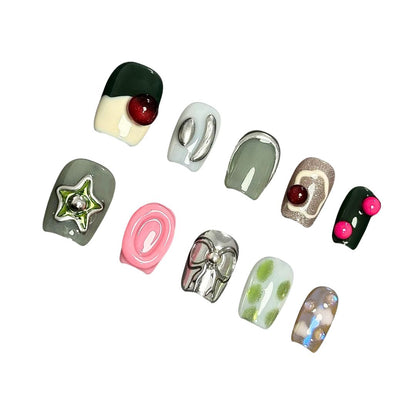 A press-on nail set featuring earthy greens, metallic silver details, and vibrant 3D elements like bows and stars, creating a modern and eclectic aesthetic.