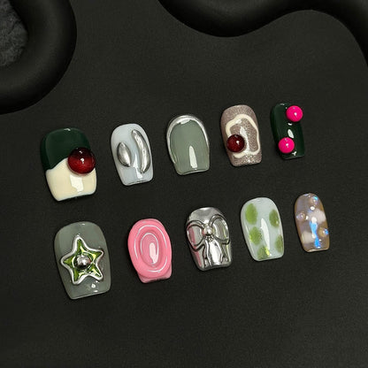 A press-on nail set featuring earthy greens, metallic silver details, and vibrant 3D elements like bows and stars, creating a modern and eclectic aesthetic.