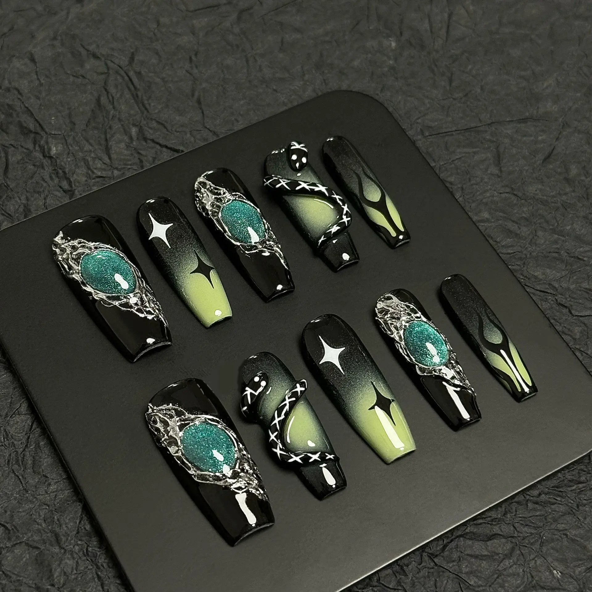 A press-on nail set featuring black and green gradients, metallic silver details, star motifs, and striking 3D embellishments, creating a mysterious and enchanting design.