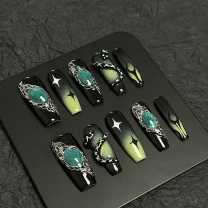 A press-on nail set featuring black and green gradients, metallic silver details, star motifs, and striking 3D embellishments, creating a mysterious and enchanting design.