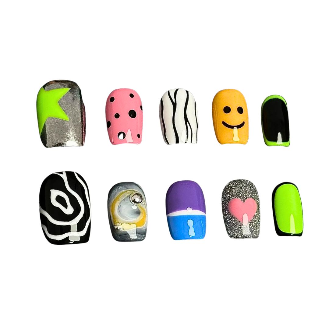 A press-on nail set featuring neon green, pink polka dots, smiley faces, abstract black-and-white patterns, and glitter accents, creating a playful and pop-art-inspired design.