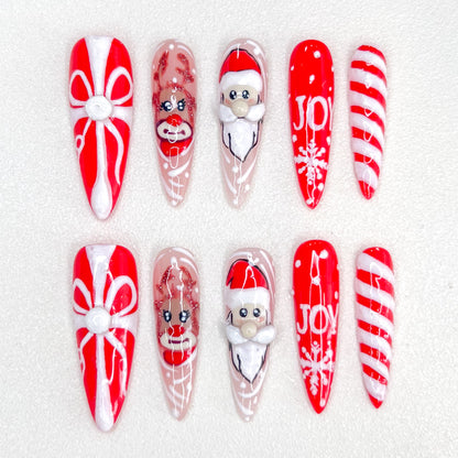 Christmas-themed press-on nails with Santa, reindeer, candy cane, gift box, and "JOY" text designs.